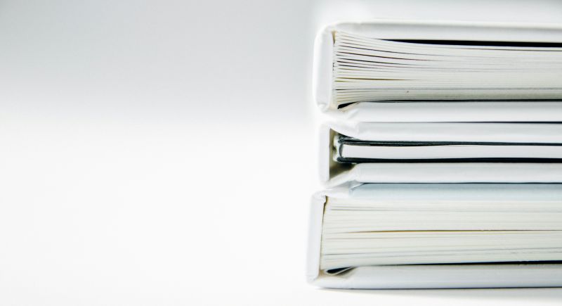 A stack of thick folders on a white surface -Foto von Beatriz Pérez Moya auf Unsplash